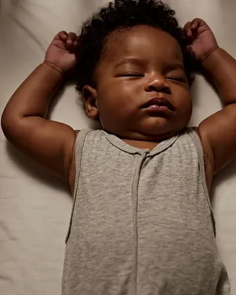 Bebê dormindo sozinho no berço, de barriga para cima