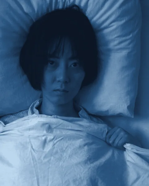 Mãe acordada na cama, de madrugada, com cara de cansaço